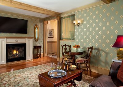 Photo of the Crown Jewel suite parlor with big screen TV above a custom made lit gas log fireplace