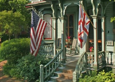 Close-up photo of The Queen Victoria front porch with the American and British flags flying.