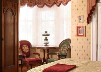 The Queen Victoria guestroom bay window sitting area with two antique embroidered chairs