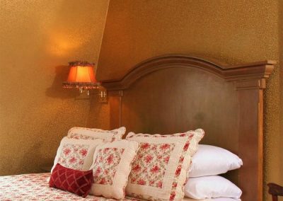 Princess Beatrice guestroom queen bed featuring a burgundy floral quilt and pillows
