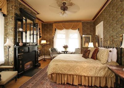 Osborne Guestroom with Queen Bed and dramatic original black carved wood mantle with marble inlay accents.