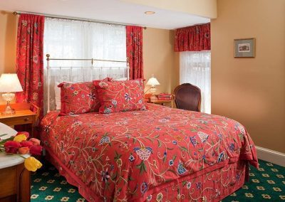 Regents Park bedroom with vibrant red floral crewel stitched bedding and draperies.