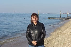 Guest Photos- Woman in black jacket standing next to the ocean.